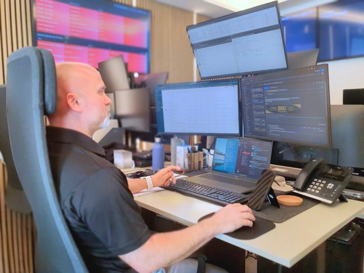 IT specialist monitoring business systems and operations across multiple screens in an office setting