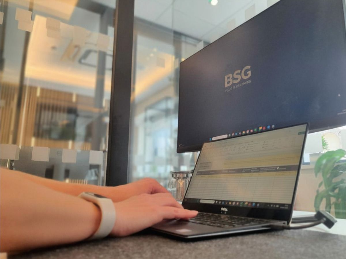 Hands typing on a laptop connected to a monitor in a modern office IT support environment