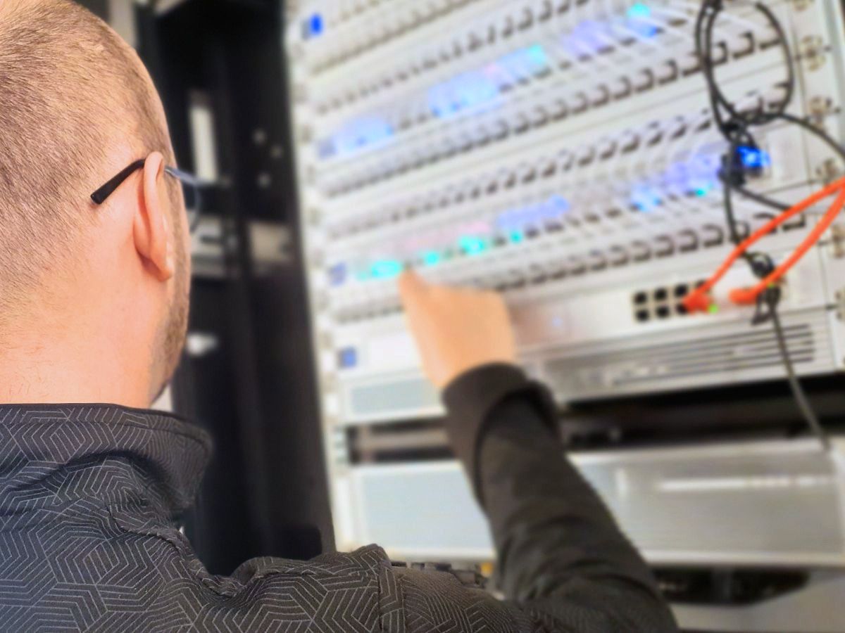 Cybersecurity and network engineer maintaining server hardware and connections in a business IT system