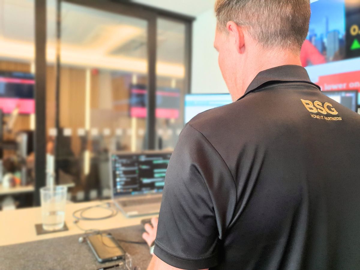 IT support specialist from BSG working at a desk with multiple monitors in a modern office